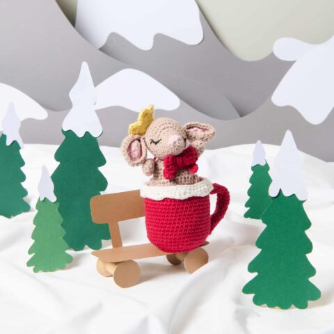 gehäkelte maus in einer gehäkelten tasse in einer winterlichen landschaft
