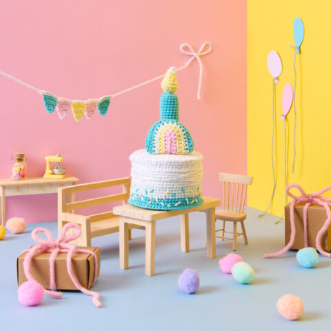 Häkelfigur Geburtstagskuchen in einer bunten Party Szenerie